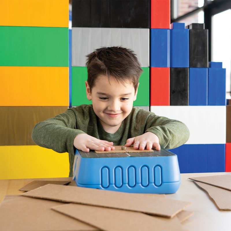 Child using the ChompSaw at a table with cardboard blocks