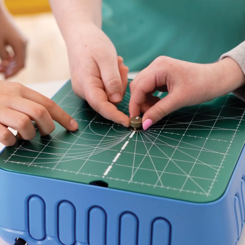 Hands feeding cardboard into the ChompSaw cutting head