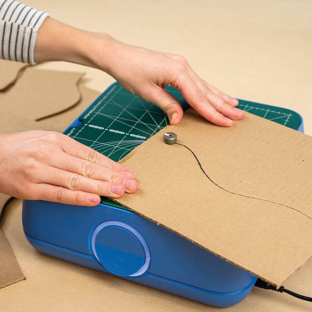 ChompSaw (3) Hands guiding a cardboard sheet through the ChompSaw