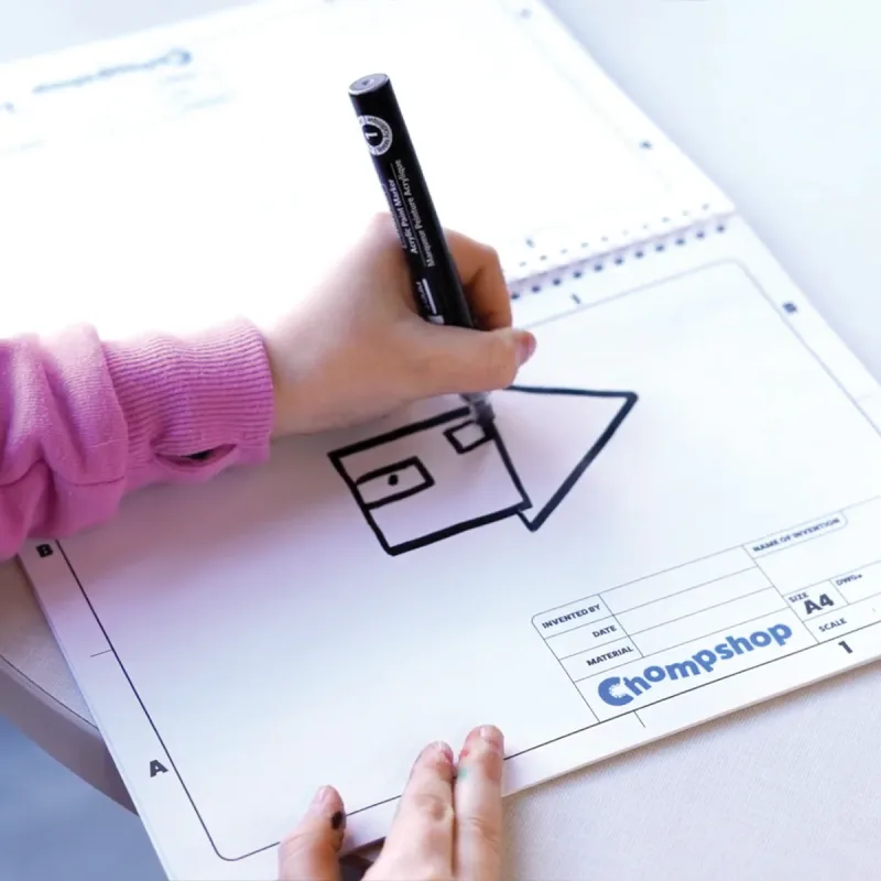 Child drawing a design in the Chompshop Inventor's Workbook