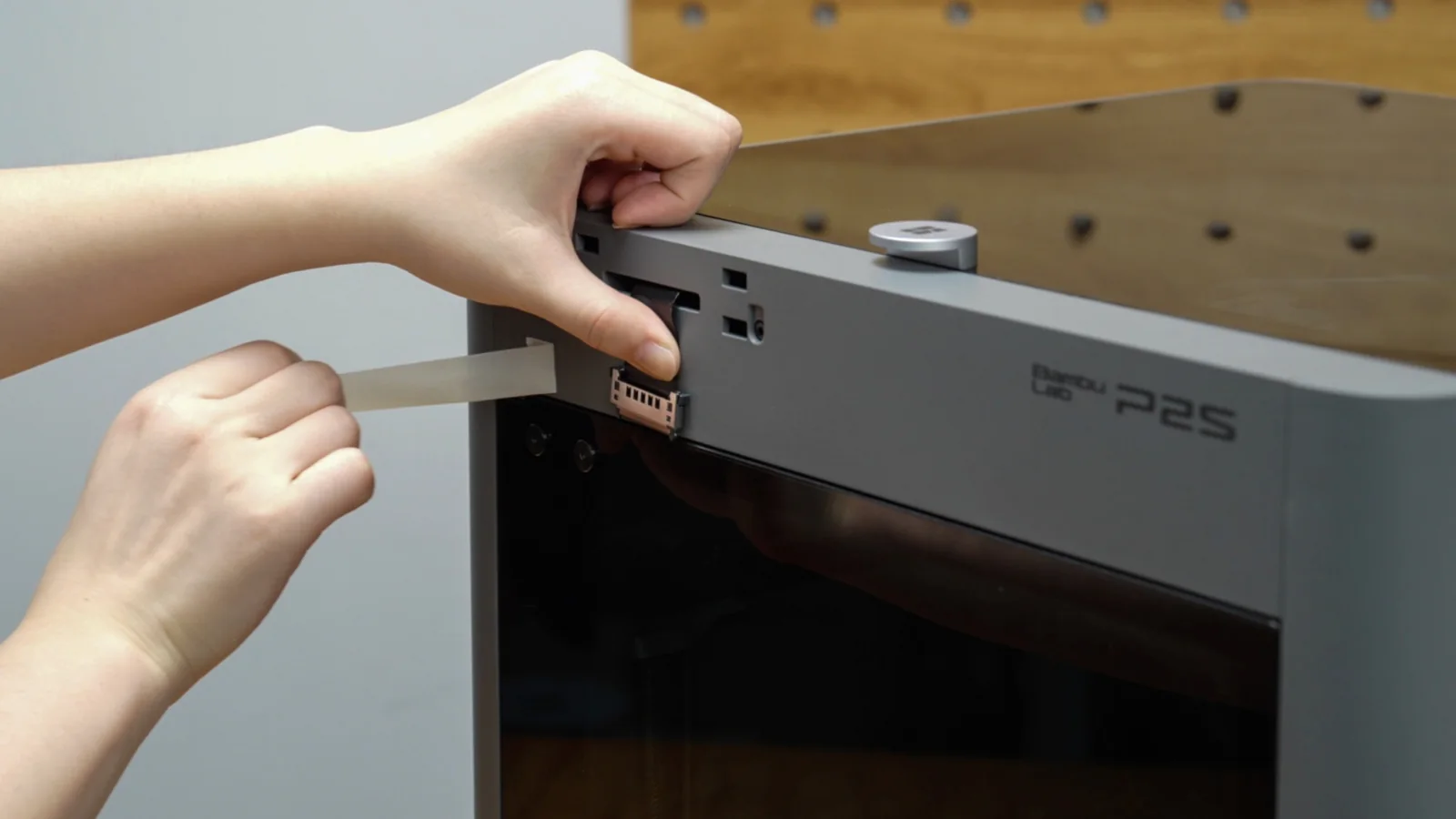 Hands sliding the build plate out of a Bambu Lab P2S