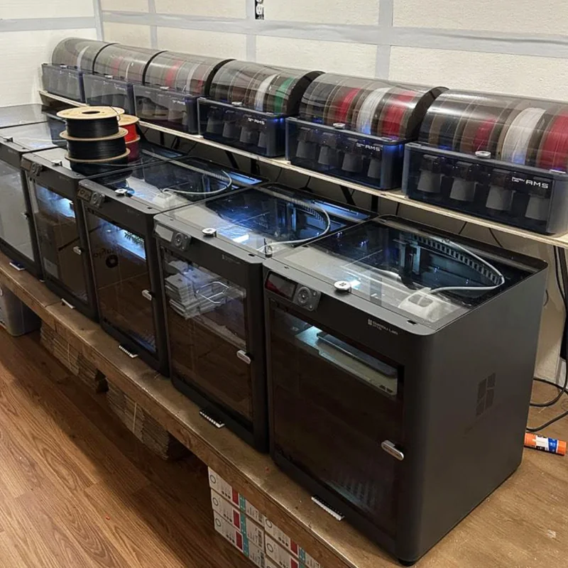 A row of Bambu Lab printers with AMS units on a workbench