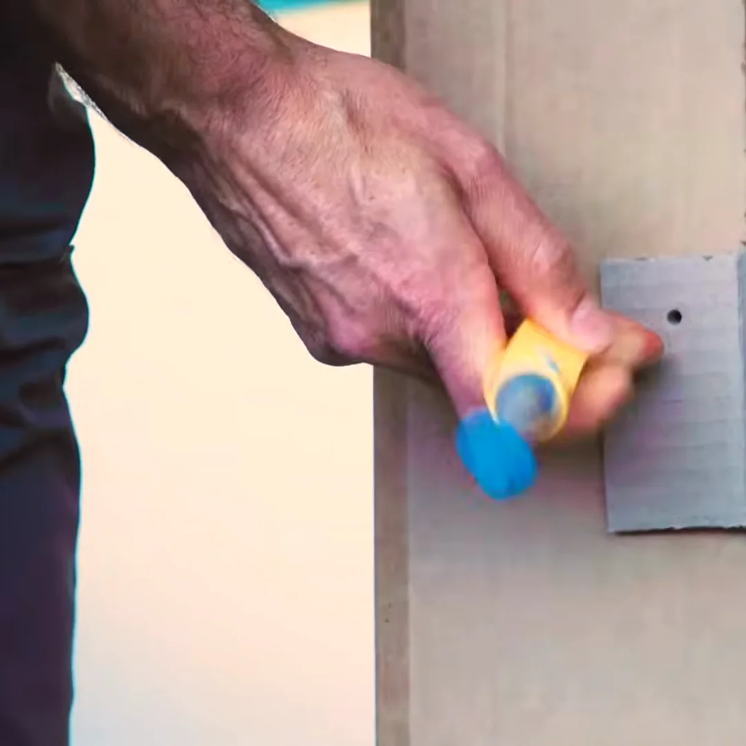 A hand pushing a Scru into a cardboard corner bracket with the Makedo Scru-Driver